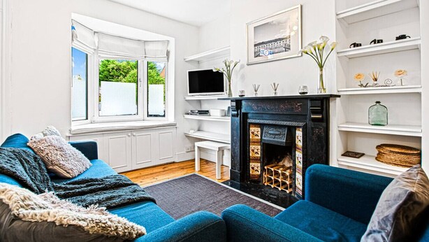 Una sala de estar moderna con chimenea, paredes blancas y sofás azules.