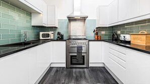 Una cocina moderna con armarios blancos, una estufa de acero inoxidable y un microondas.