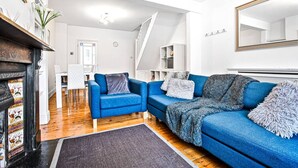 Una sala de estar moderna con un sofá azul, una chimenea y una escalera que lleva a otro nivel.