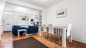 Una sala de estar moderna con un sofá azul, una mesa de comedor con sillas y un ventanal grande.