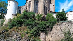 A historic stone building with a tower, situated beside a river with a rocky foreground. - House for rent by the river in a peaceful hamlet (Saint-Cirgues)