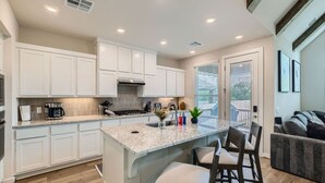 A modern kitchen with white cabinets, a granite countertop, and a central island with bar stools.