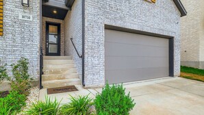 A two-story house with a brick exterior, a front door, and a garage.