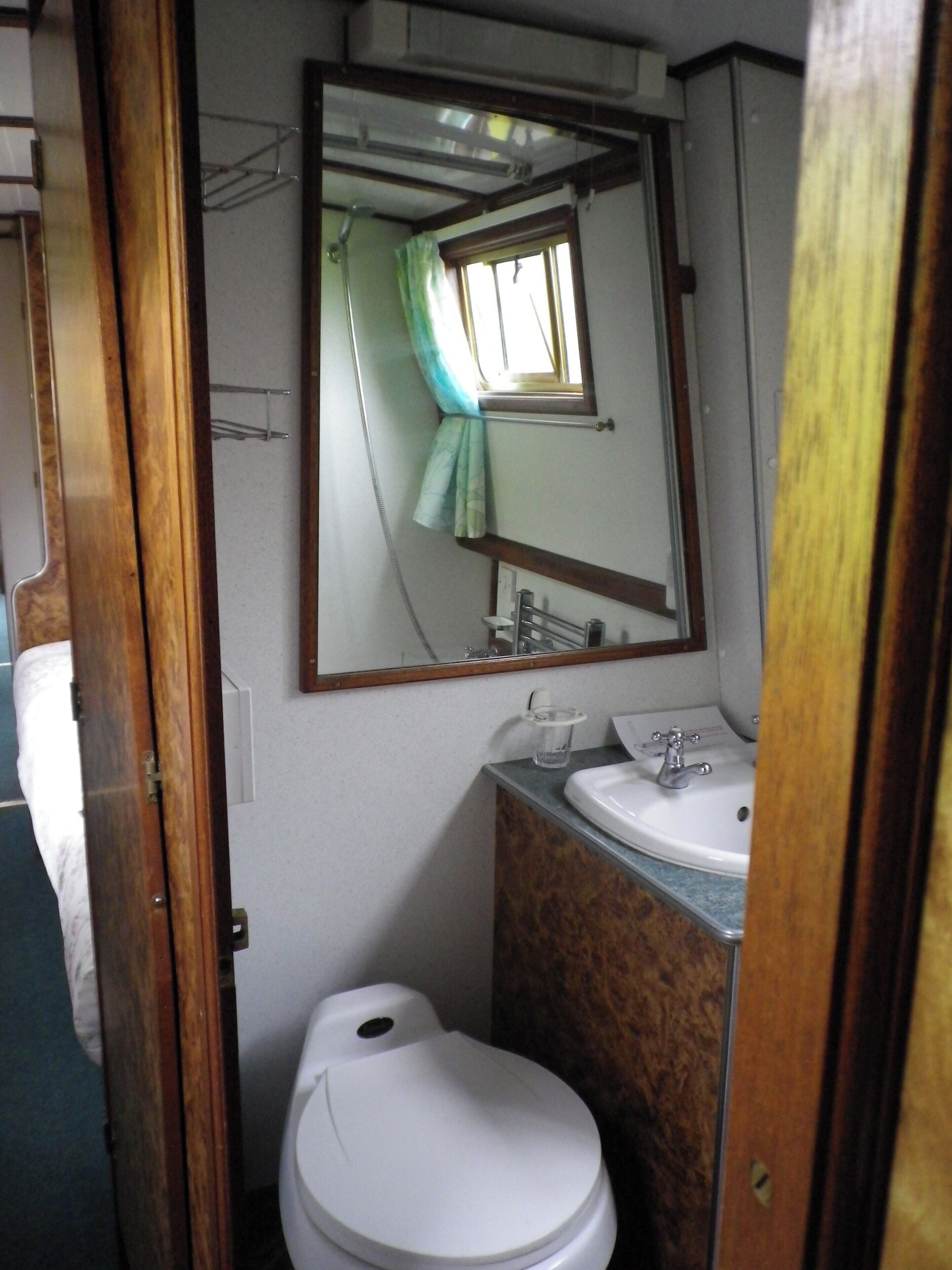 A compact bathroom with a toilet, sink, and mirror.
