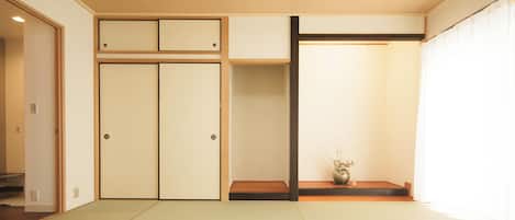 A traditional Japanese room with tatami flooring, sliding doors, and a small table with a vase.