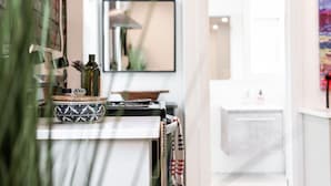 A modern kitchen with a white countertop, a decorative bowl, and a mirror above it. - The Hawthorne Apartment (Stratford)