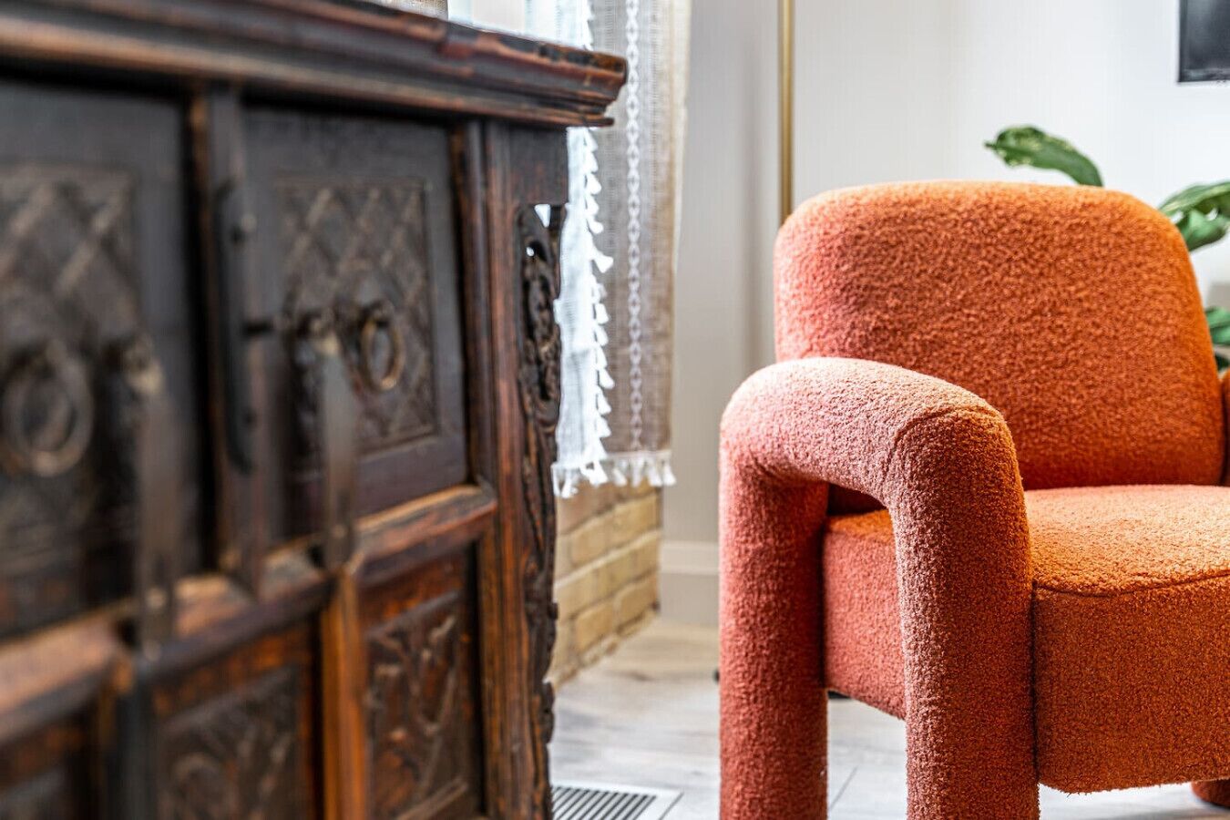 Quarto com um armário de madeira e uma cadeira laranja com textura.