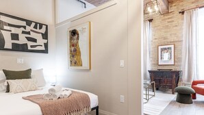 Un dormitorio moderno con una cama, almohadas, una colcha y una obra de arte en la pared.