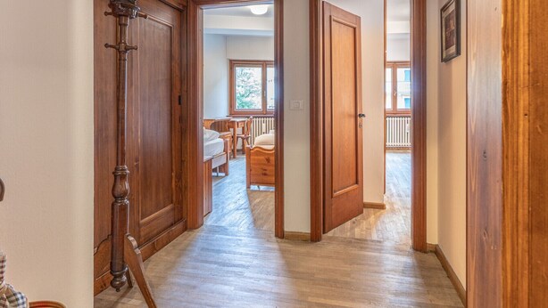 Un pasillo con piso de madera y puertas que dan a un dormitorio y un baño.