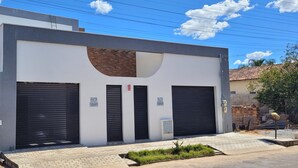 A modern building with two large black garage doors, a brick section, and a clear sky.