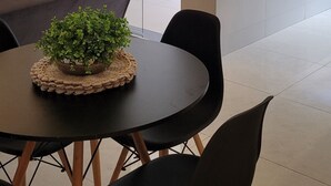 A conference room with a round table, black chairs, and a potted plant.