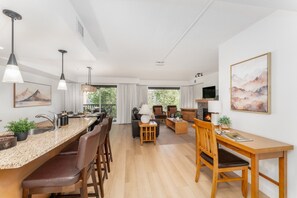 A modern kitchen with a dining area, a fireplace, and a living room with a sofa and coffee table. - Copper Point - Outdoor Hot Tub | Fire Table | Gym (Dead Man`s Flats)