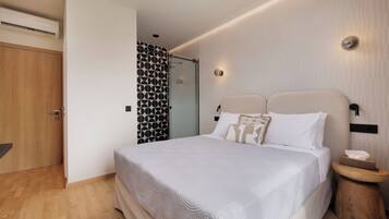 Un dormitorio moderno con una cama grande, una puerta de madera, una zona de ducha y una pared con un diseño geométrico.