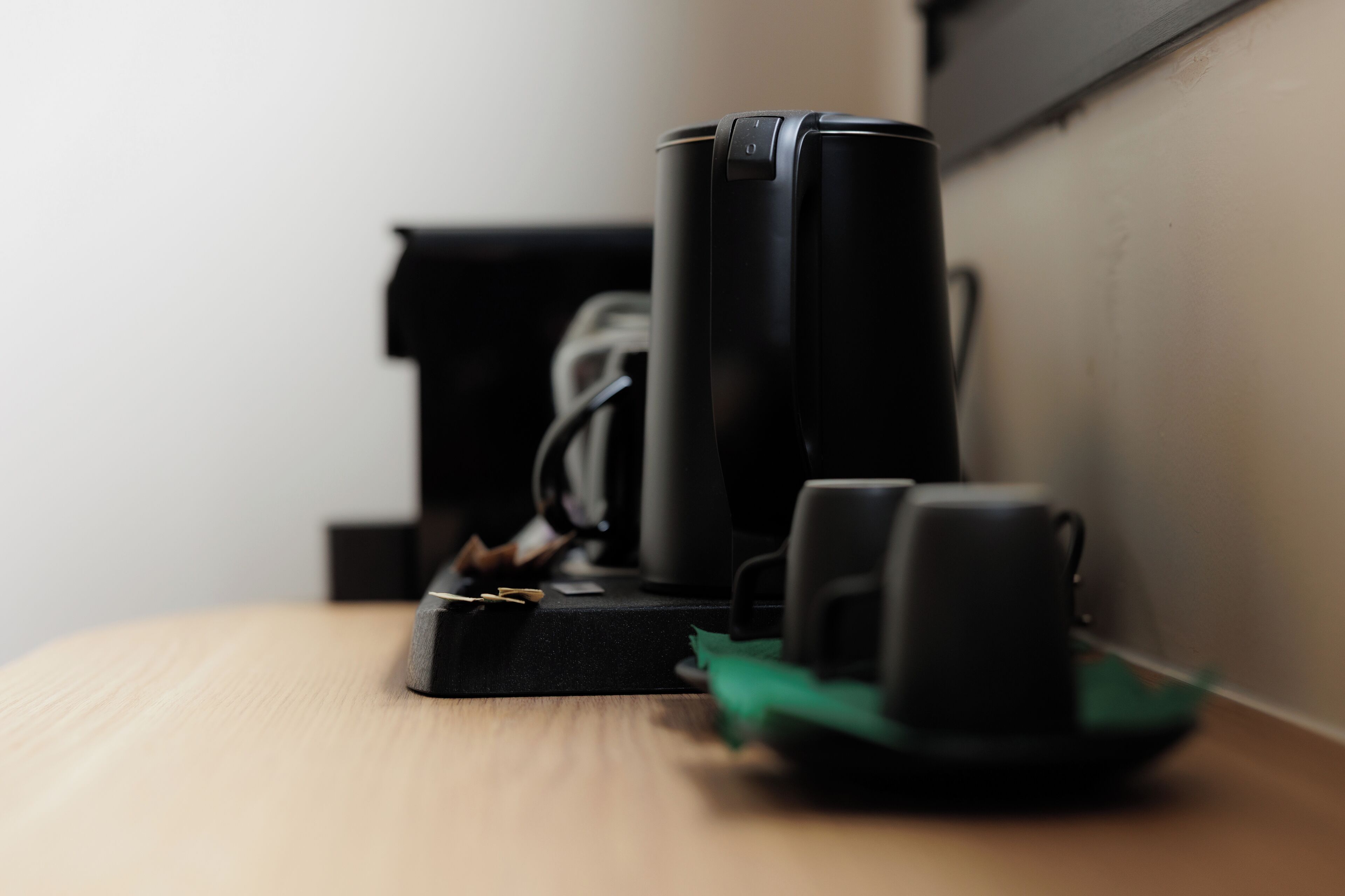 Eine schwarze Kaffeemaschine auf einem Holztisch mit einem grünen Untersetzer.