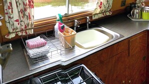 A kitchen with a window, a sink, and a clock on the wall. - Stone - Boat - Sleeps 6 - Pet Friendly - 85ws (Stone)