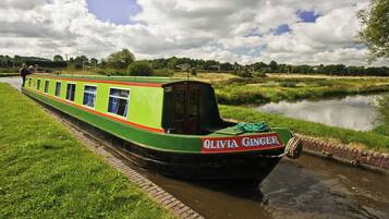 A narrowboat named "OLIVIA GINGER" docked at a canal.