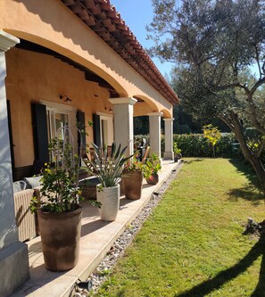 Une maison dotée d’un porche abrité, de plantes en pot et d’une pelouse bien entretenue.