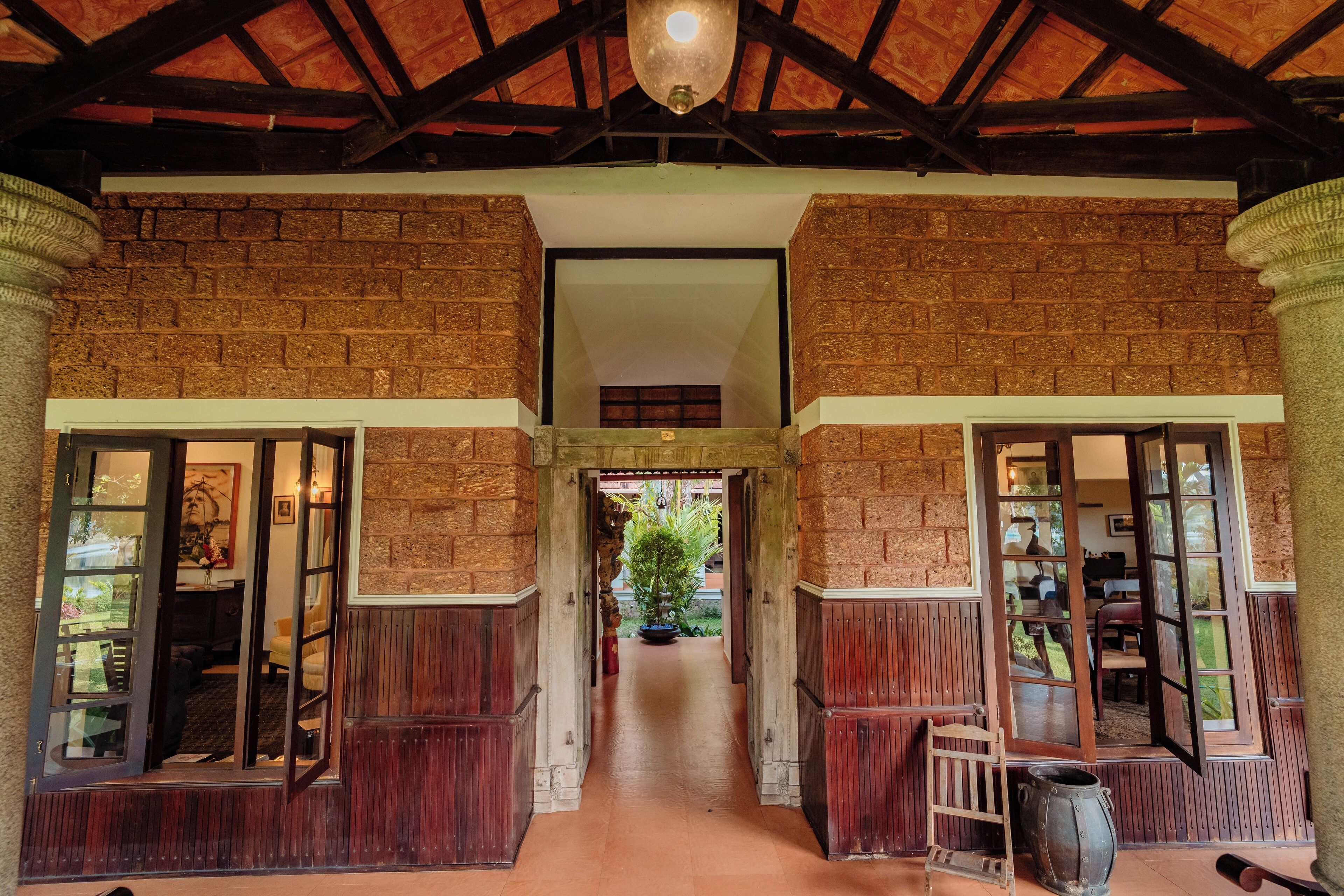 A corridor with brick walls, wooden doors, and a ceiling with exposed beams.