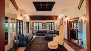 Un salón amplio con un sofá azul oscuro, un sillón blanco y una alfombra grande.