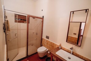 Ein Badezimmer mit einer Duschkabine, einer Toilette und einem Waschbecken mit Spiegel darüber.