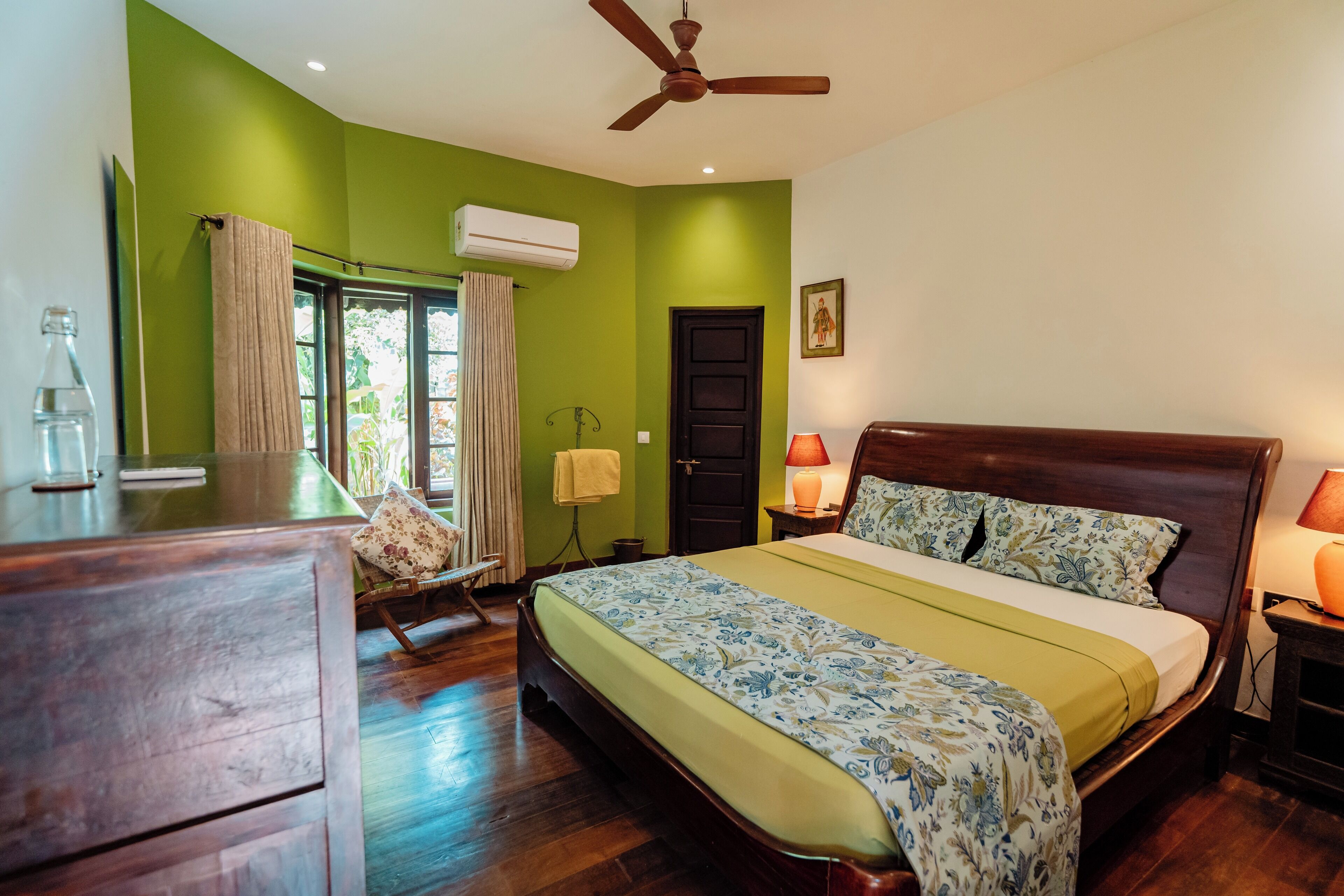 Un dormitorio con cama, muebles de madera, ventilador de techo y ventana con cortinas.