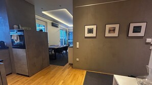 Een moderne keuken met houten vloeren, een eethoek met een tafel en stoelen, en afbeeldingen in lijsten aan de muur.