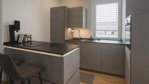 Een moderne keuken met een geïntegreerd kookeiland, een spoelbak en een raam met zonwering.