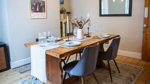 A dining area with a wooden table set for four, surrounded by chairs. There is a vase with flowers on the table, and a candle is lit. - The Mount Street Townhouse (Harrogate)