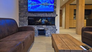 Una sala de estar moderna con una chimenea de piedra, un televisor de pantalla plana montado encima y dos sofás de cuero.