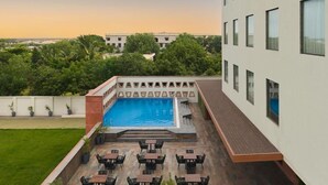 A rooftop pool with a view of surrounding buildings and greenery. - Regenta Central Shivani Solapur (Mohol)