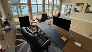 Un bureau spacieux avec de grandes fenêtres, un bureau, deux chaises et une vue sur l’extérieur.
