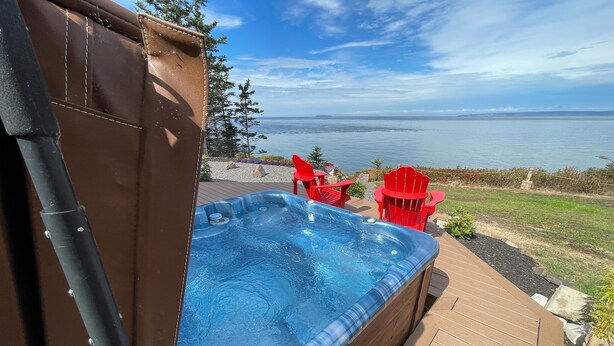 Un bain à remous sur une terrasse en bois, avec vue sur l’océan.