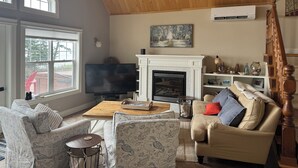 Un salon avec une cheminée, un téléviseur et un plafond en bois.