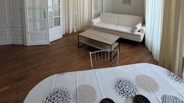 A spacious room with a white sofa, a small table, and a patterned tablecloth. - Paris 15 Beau 2 bedrooms, living room, ground floor. Wifi, net, Pets allowed. (Paris)
