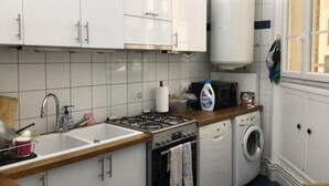 A kitchen with white cabinets, a sink, a stove, a microwave, and a washing machine. - Paris 15 Beau 2 bedrooms, living room, ground floor. Wifi, net, Pets allowed. (Paris)