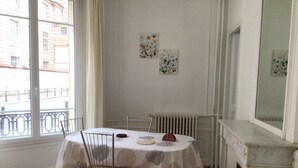 A dining area with a table set for four, a dog lying under the table, and a fireplace to the right. - Paris 15 Beau 2 bedrooms, living room, ground floor. Wifi, net, Pets allowed. (Paris)