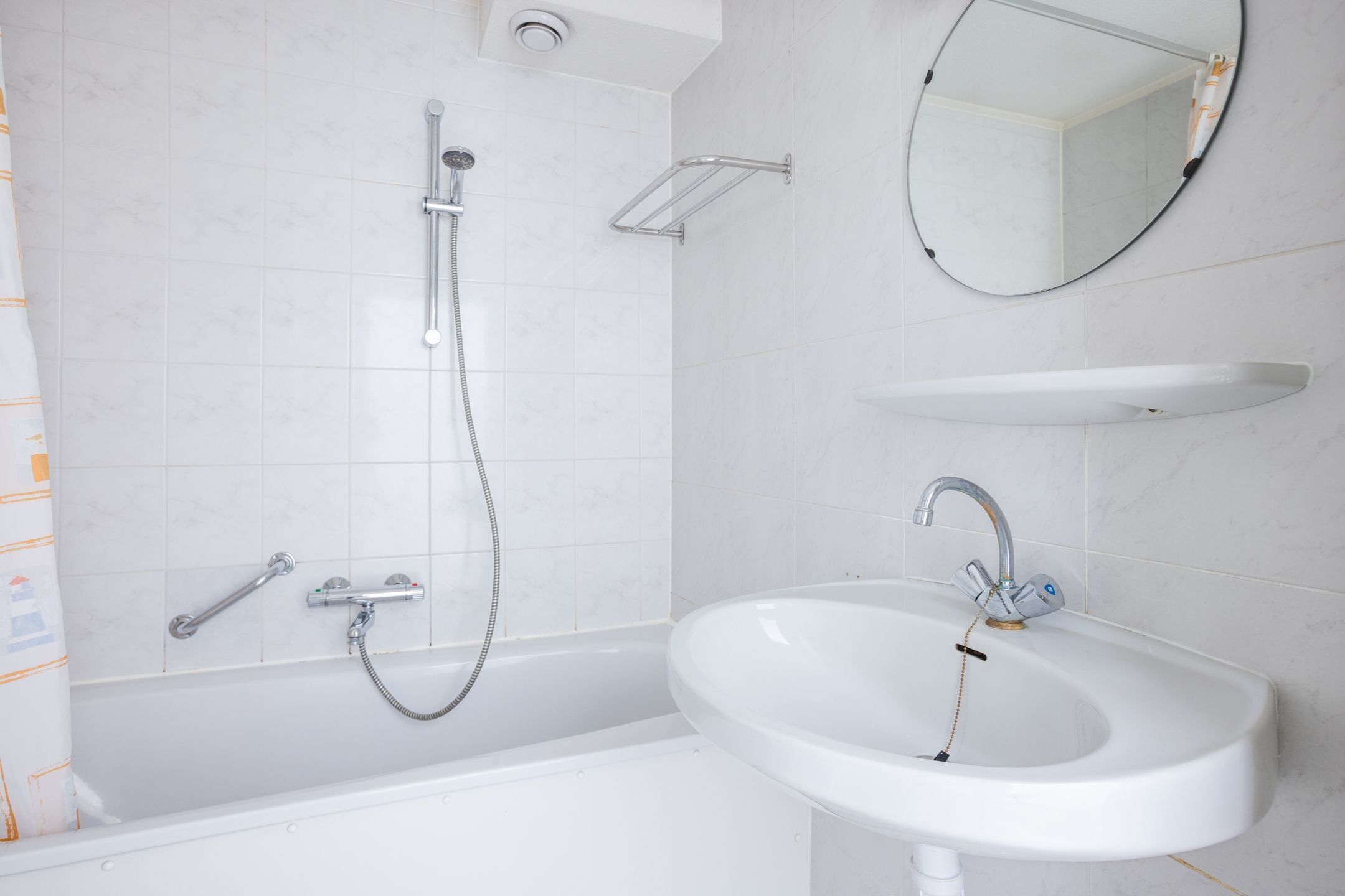 Un bagno moderno con vasca, lavandino, soffione della doccia e specchio.