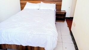 A neatly made bed with a wooden headboard in a small, clean room.
