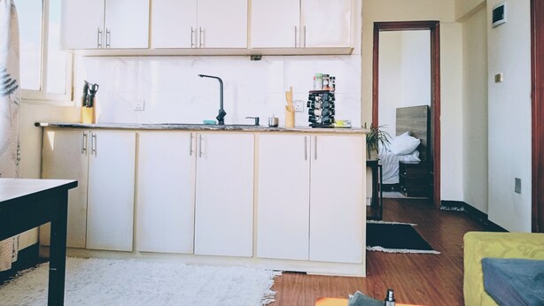 A kitchen with white cabinets, a black faucet, and a countertop with various items.