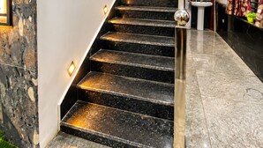 A modern staircase with a glass railing, leading to a landing with a potted plant. - Hotel Mero Vrindavan (Vrindavan)