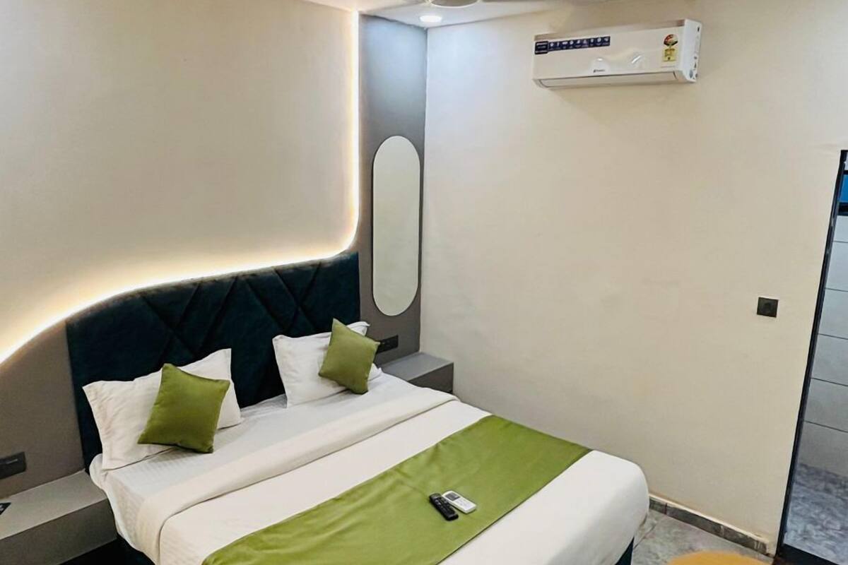 A modern bedroom with a bed, bedside tables, a ceiling fan, an air conditioning unit, and a small wooden table.