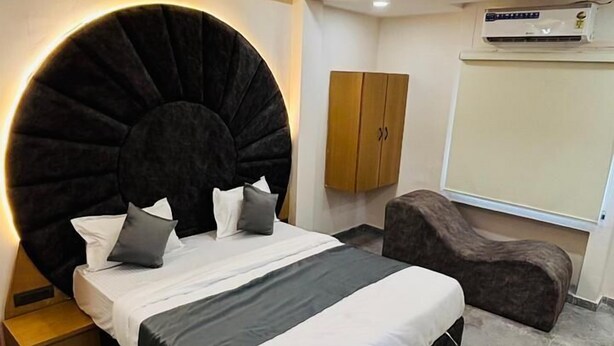 A modern bedroom with a large bed, a round coffee table, a sofa, and a ceiling fan. - Hotel kings villa (Ahmedabad)