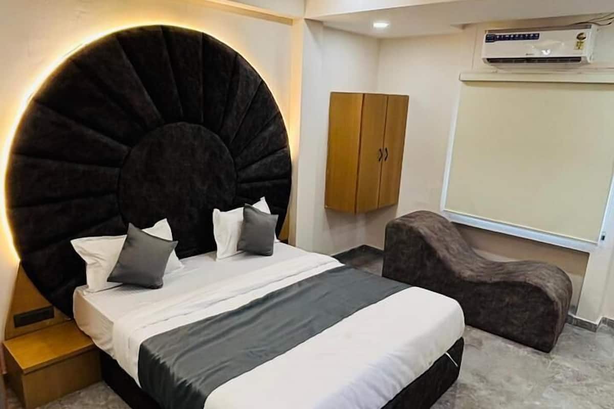 A modern bedroom with a large bed, a round coffee table, a sofa, and a ceiling fan.