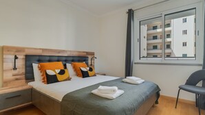 Ein Hotelzimmer mit Bett, Stuhl, Nachttisch und Fenster mit Blick auf andere Gebäude.