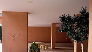 A courtyard with a central round table surrounded by four smaller tables, a potted plant, and a tree. - Fabi Beach Apartment (Torrevieja) (Torrevieja)