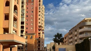 A swimming pool surrounded by multi-story residential buildings with balconies and a clear sky. - Fabi Beach Apartment (Torrevieja) (Torrevieja)