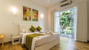 A hotel room with a large bed, a bedside table with a phone, and a view of the outdoors through a sliding glass door.