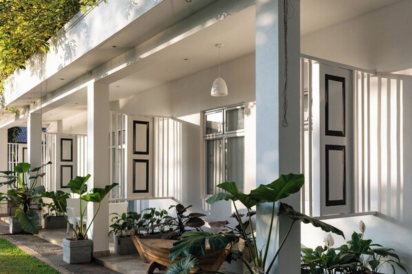 Un espacio al aire libre cubierto con plantas en macetas, un banco de madera y una barandilla blanca.