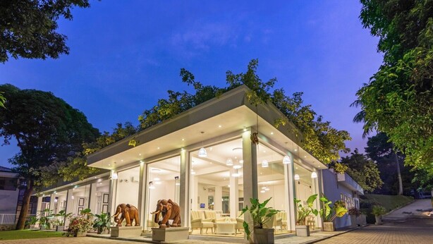 A modern building with a glass facade, a covered outdoor area with seating, and elephant sculptures.