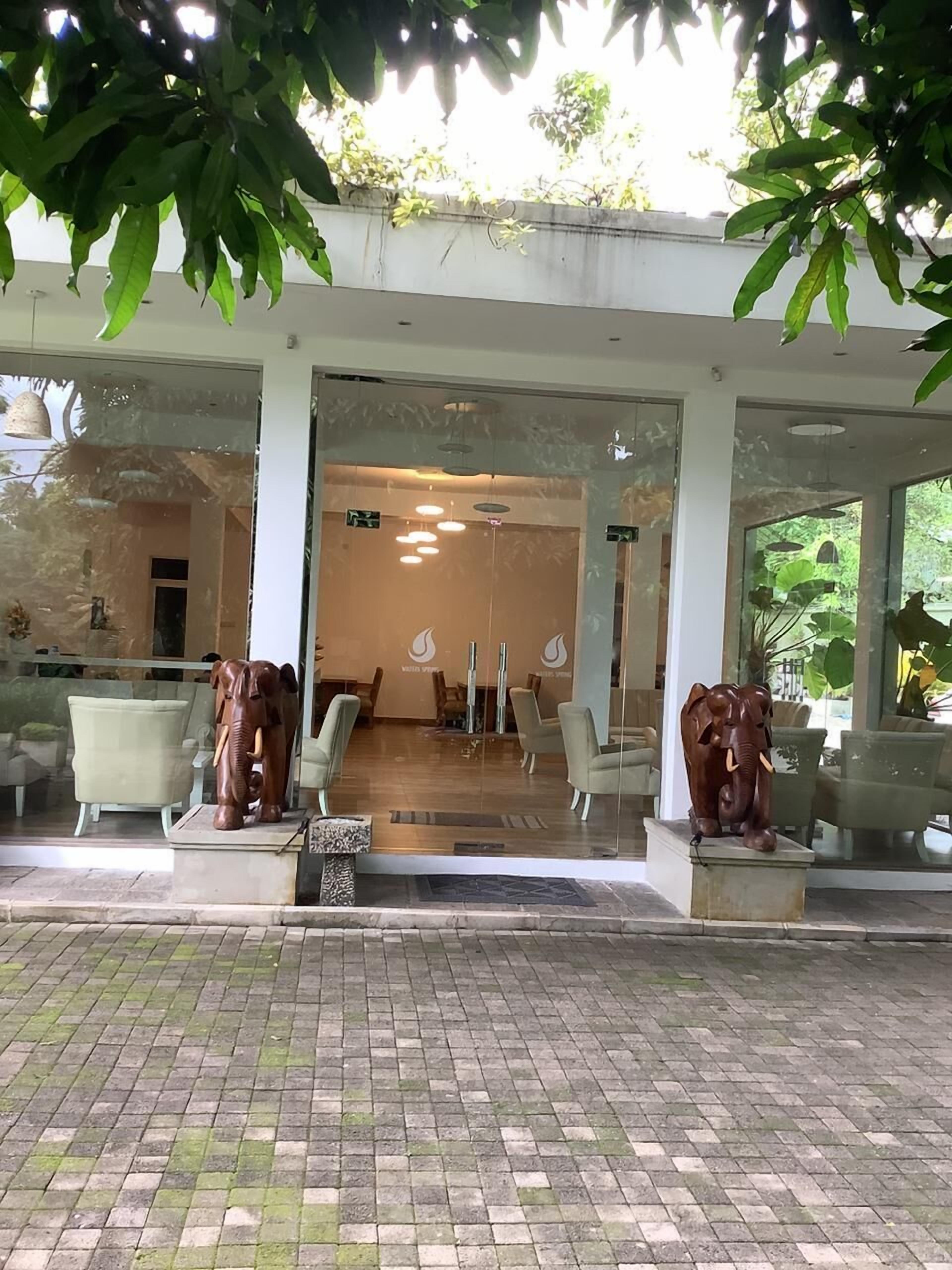 A building entrance with two elephant statues, a reception area with chairs, and a tiled floor.
